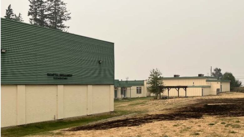 School building with sign 'North Shuswap Elementary' with a large grassland near it.