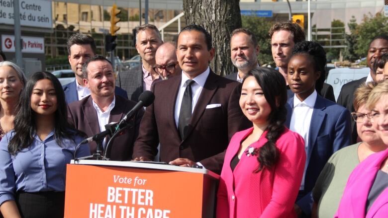 Manitoba NDP Leader Wab Kinew surrounded by NDP candidates during a campaign announcement outside a hospital.