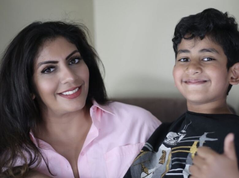 A woman wearing a pink dress shirt and a young boy.