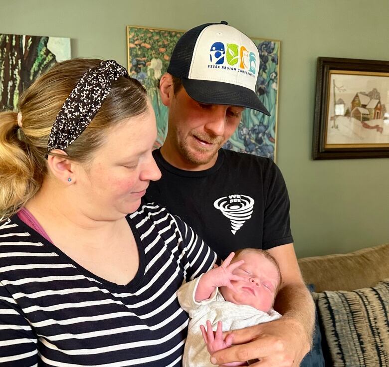 A mother and father hold their newborn baby daughter.