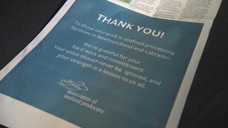 A newspaper ad reads 'Thank you! To those who work in seafood processing facilities Newfoundland and Labrador. We're grateful for your hard work and commitment. Your voice should never be ignored, and your strength is a lesson to us all.'