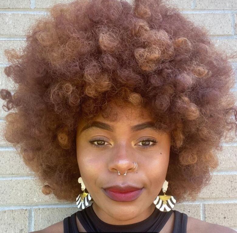 A black African woman with afro hair and African print earrings.