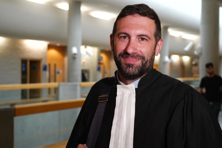 A man in court robes smiles into the camera.