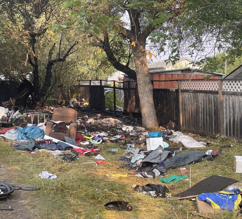 Destroyed furniture and burned clothes lying in a plot. 