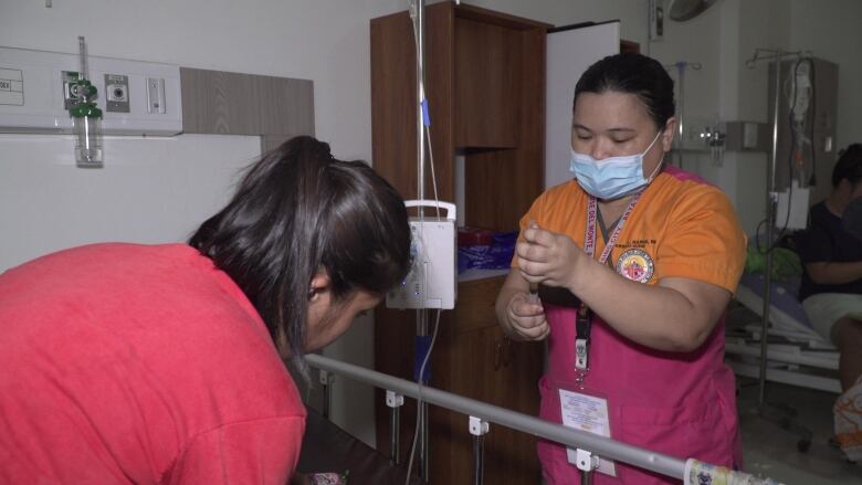 A nurse in scrubs prepares medication.