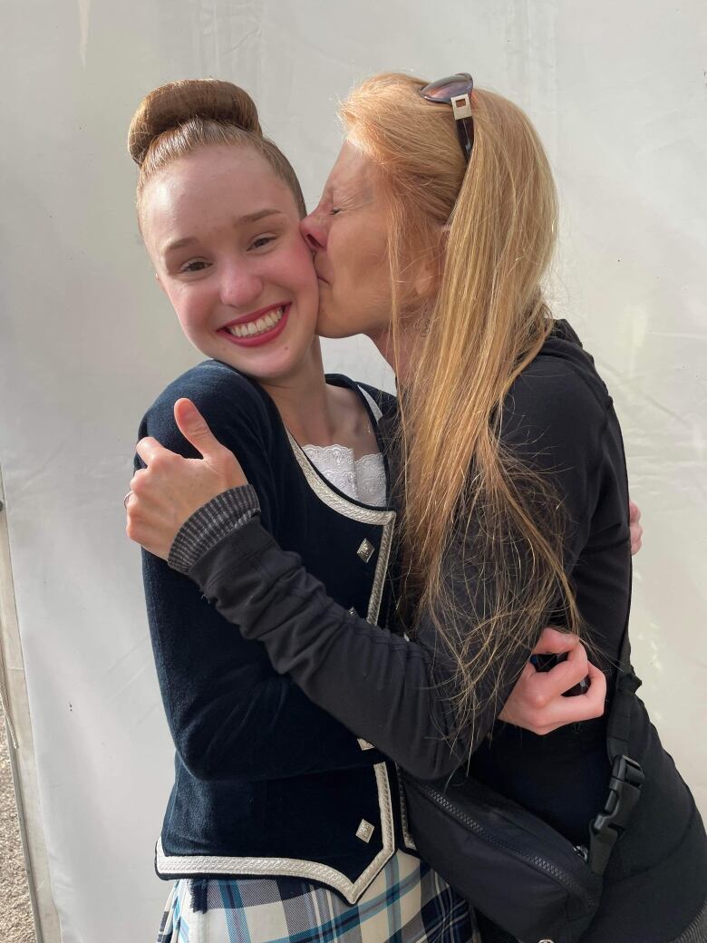 Two women are seen celebrating a win in competitive highland dancing. 