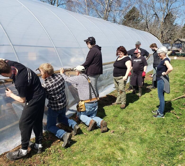 A group of people repairing a greenhouse