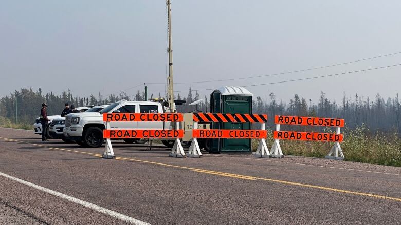 Trucks and orange signs that say road closed