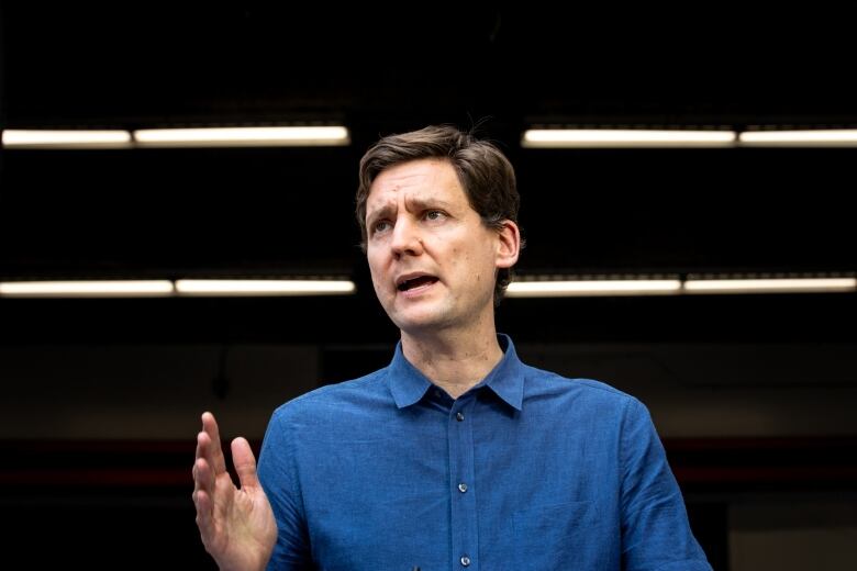 A man in a blue shirt raises his hand and speaks.