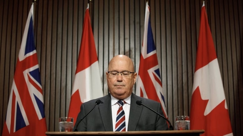 A man speaks behind a podium at a press conference.