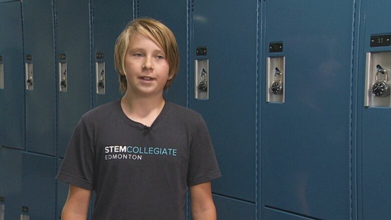 A student stands in front of lockers.