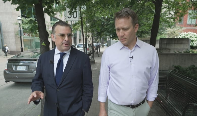 Two men walk down the street. 