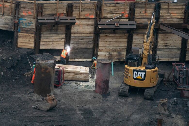 Two workers are shown on a construction site.