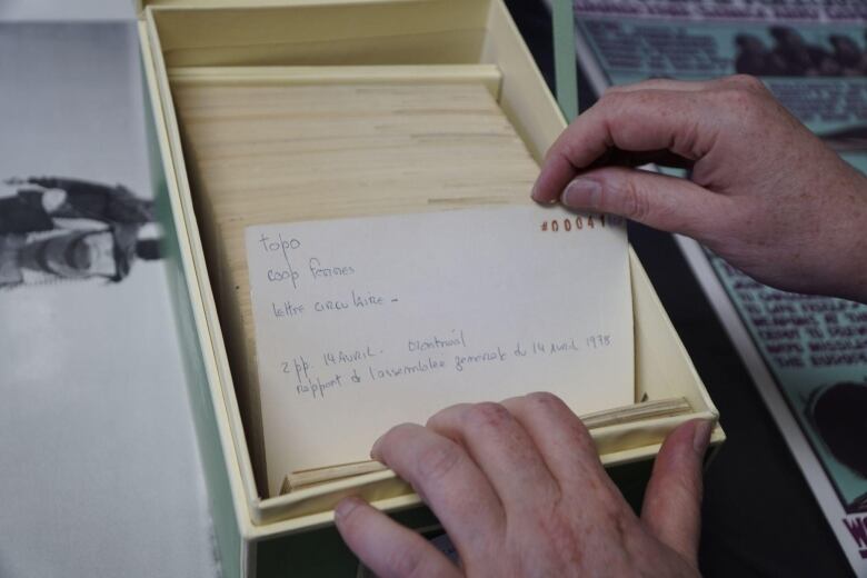 a woman's hands flipping through index cards