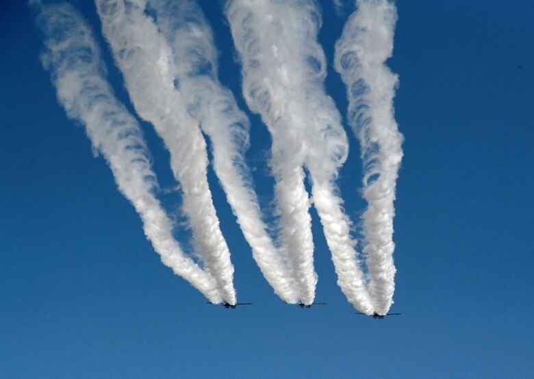 Three fighter jets with Indian Air Force performing in the sky.