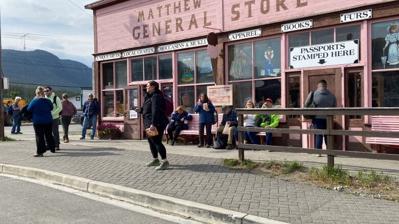 People are shown congregating outside a store that has a sign that reads 