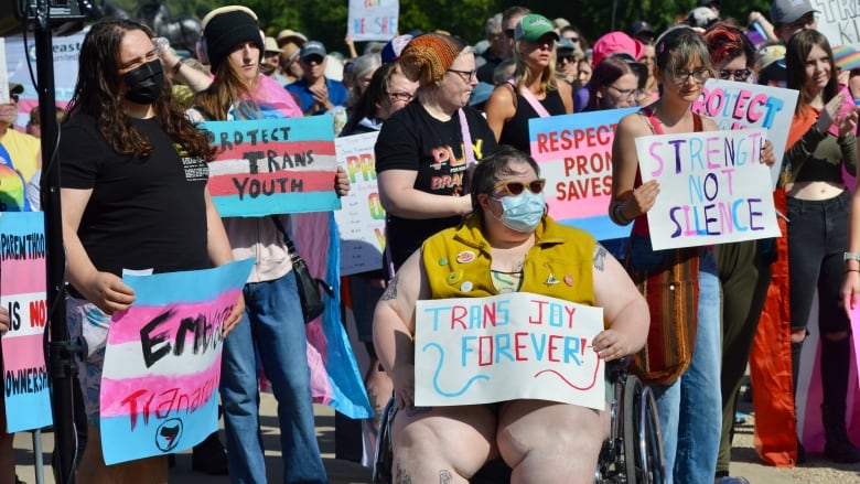 People lined up in front of the Saskatchewan Legislative Building with pro-transgender posters 