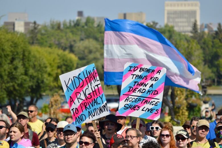 Two signs in the air above a crowd of people. One reads Kids have a right to privacy and autonomy. The second read I'd rather a trans kid than a dead kid, acceptance saves lives 