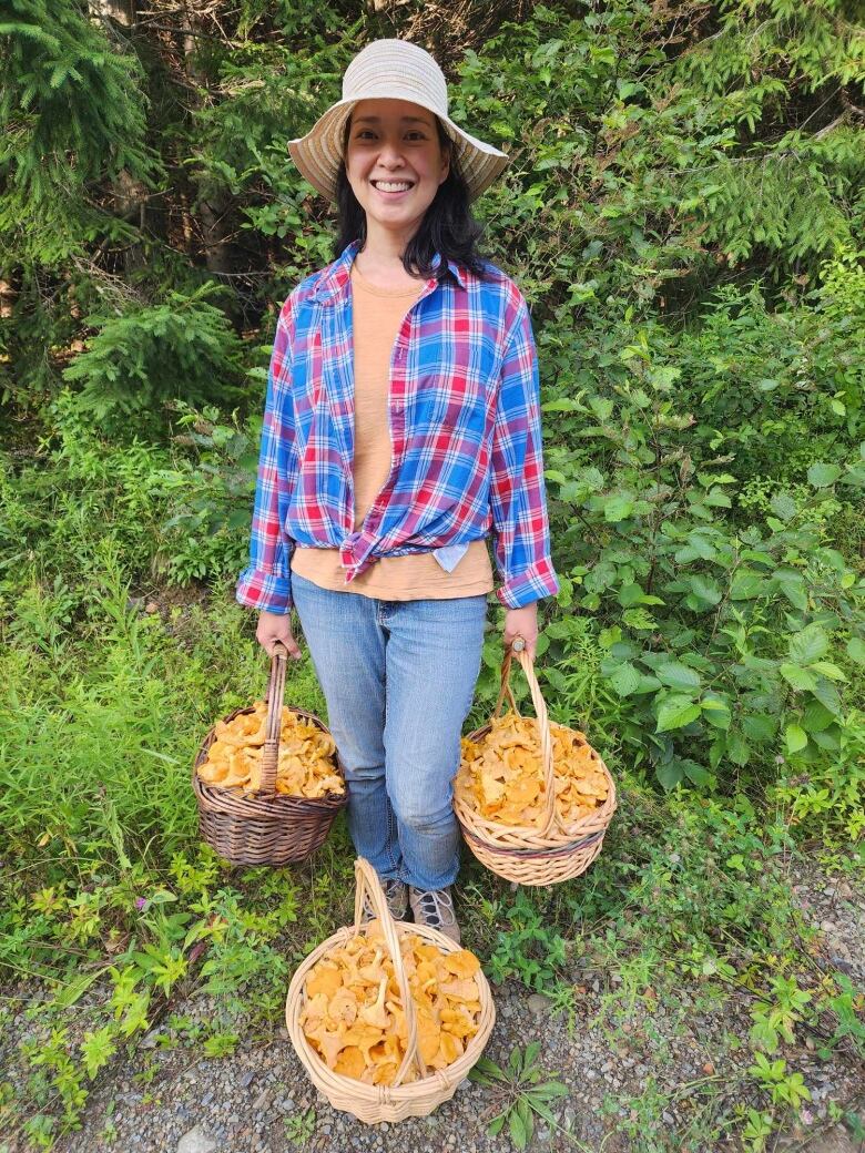 A woman holding three baskets full of chanterelles