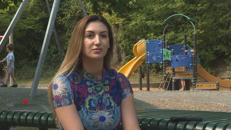 A woman sits at a picnic table at a park.