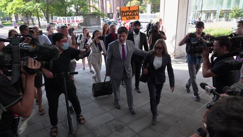 A woman walks into a courthouse surrounded by people in late summer.