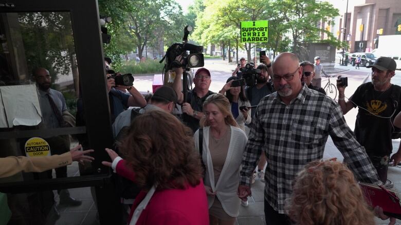 A man walks into a courthouse surrounded by people in late summer.