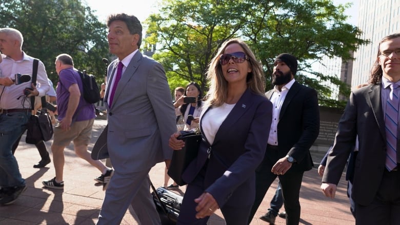 A woman smiles as she walks into court with her lawyer.