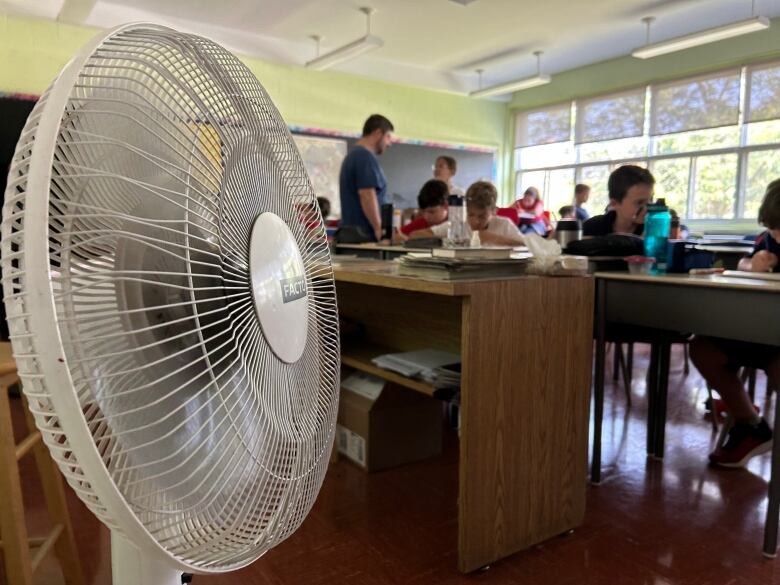 A fan blowing in a classroom with kids. 