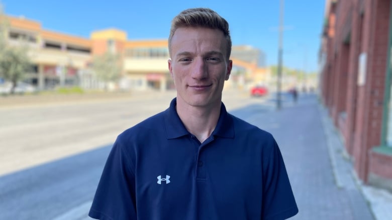 A young man wearing a blue short-sleeved shirt.