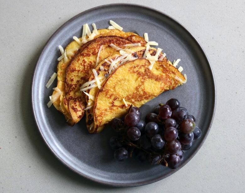 Cachapas, also known as Venezuelan pancakes on a plate with grapes.