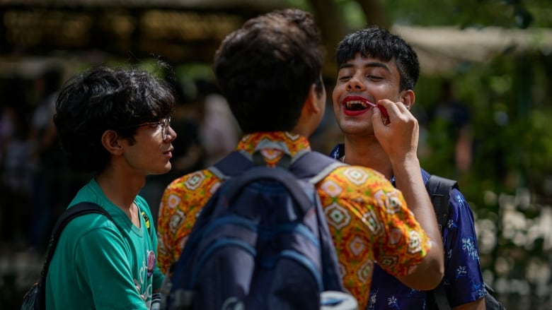 A participant applies lipstick on another during an event.