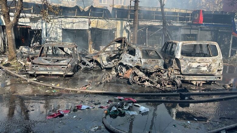 Destroyed cars sit at the site of a Russian strike on a market in a Ukrainian city.