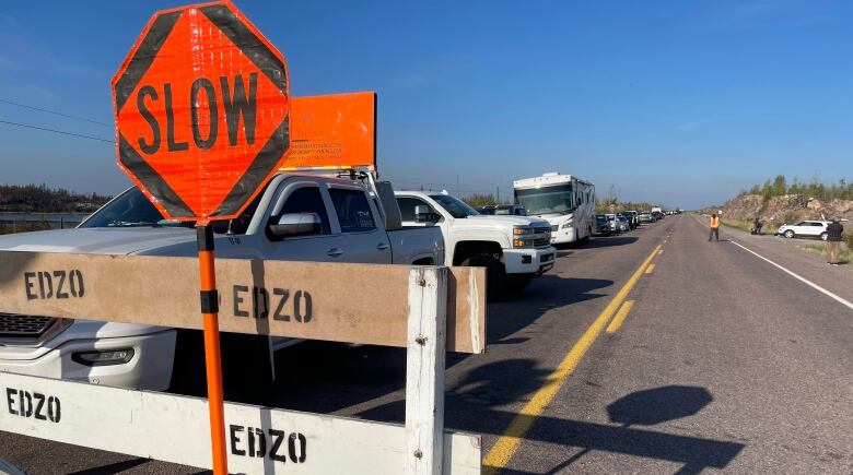 A line up of cars behind a road block. 