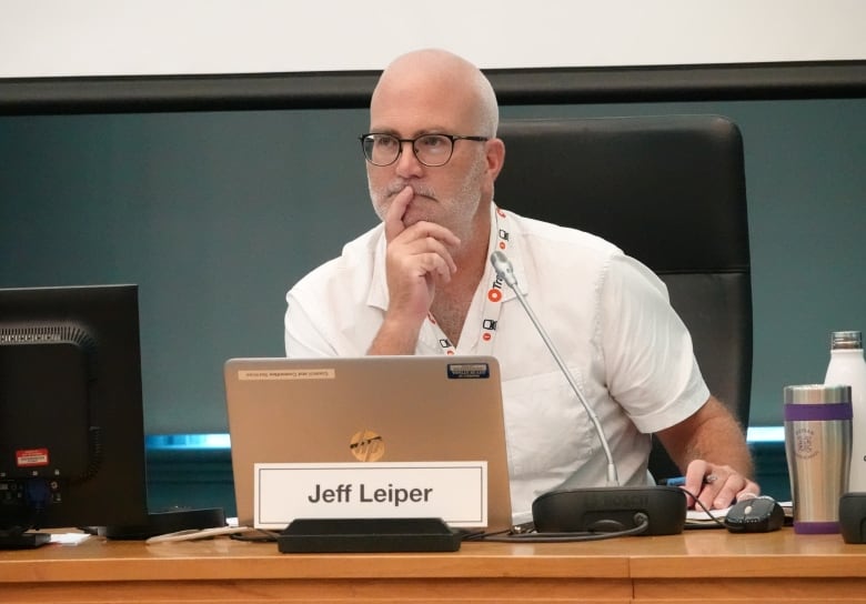 A city councillor sits at a table and listens during a meeting.