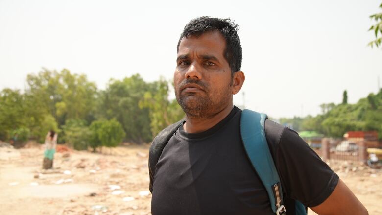 A person stands in front of rubble on a lot where a shelter was demolished.