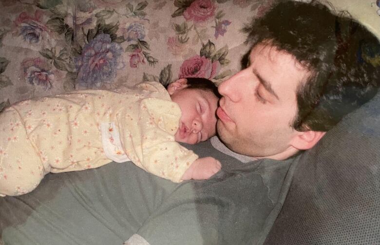 A man with a baby on his chest.