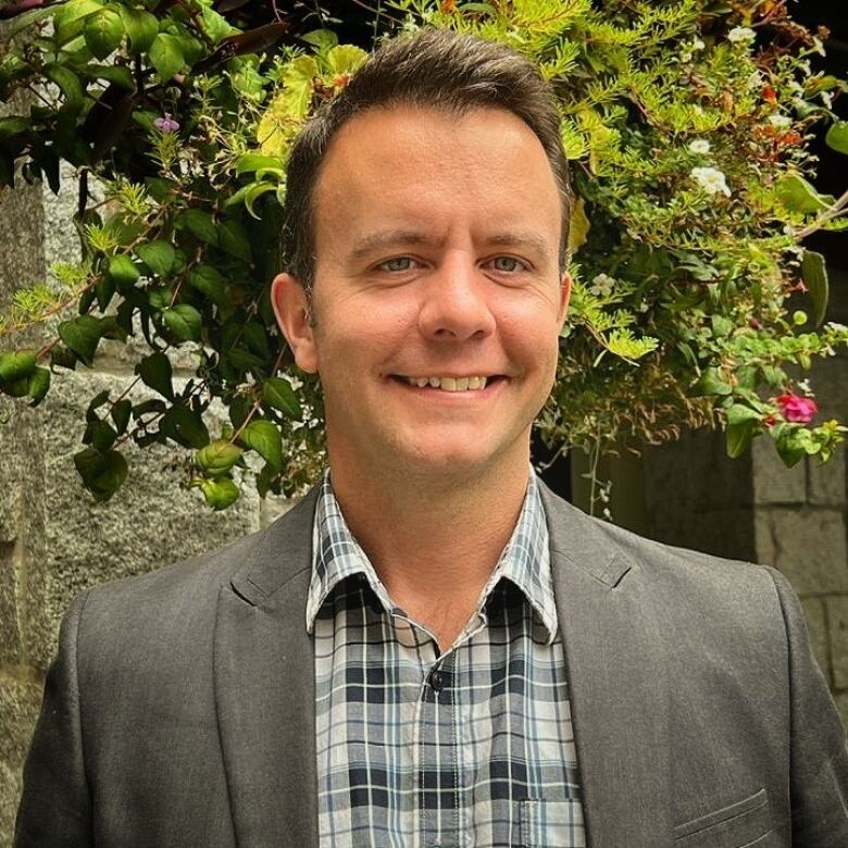 A white man smiles in a suit.