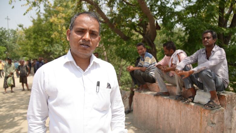 A longtime social activist stands near the New Delhi site where a shelter used to stand, surrounded by the homeless men who used to stay there. 