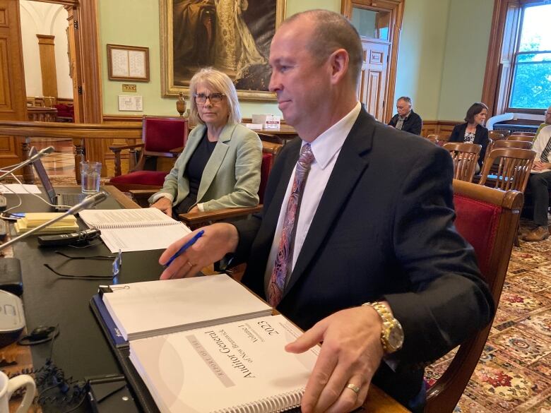 A man and a woman sit at a desk in the legislature.