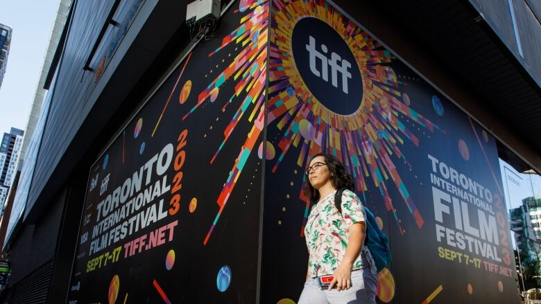 A woman walks by a TIFF (Toronto International Film Festival) sign.