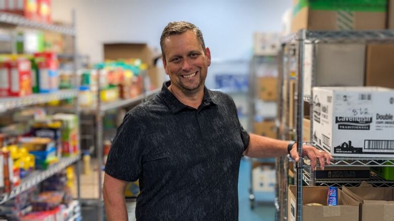 A man standing next to shelves of food 