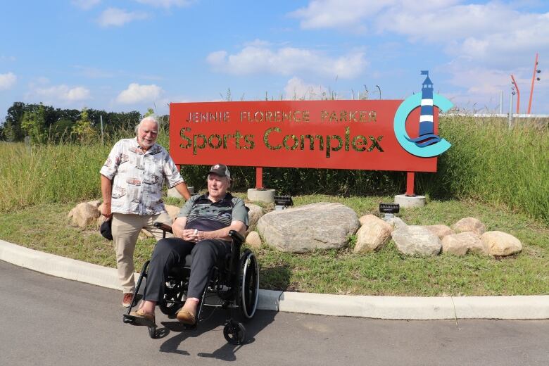 Two men in front of a sign. 