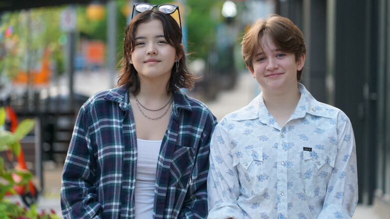 Two young people stand side by side posing for a photo.