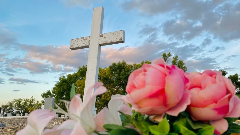 Image of a headstone in a cemetery with flowers.