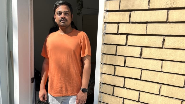 A man stands in a doorway of his apartment.