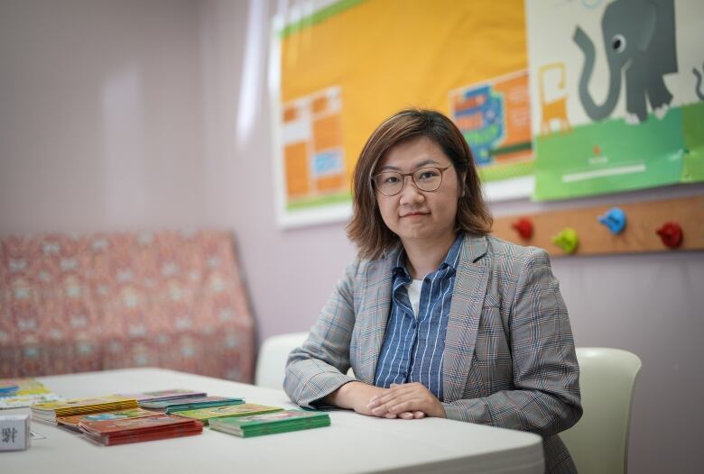 A woman is seated and looks at the camera.