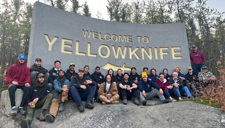 Two dozen men and women pose in front of a 