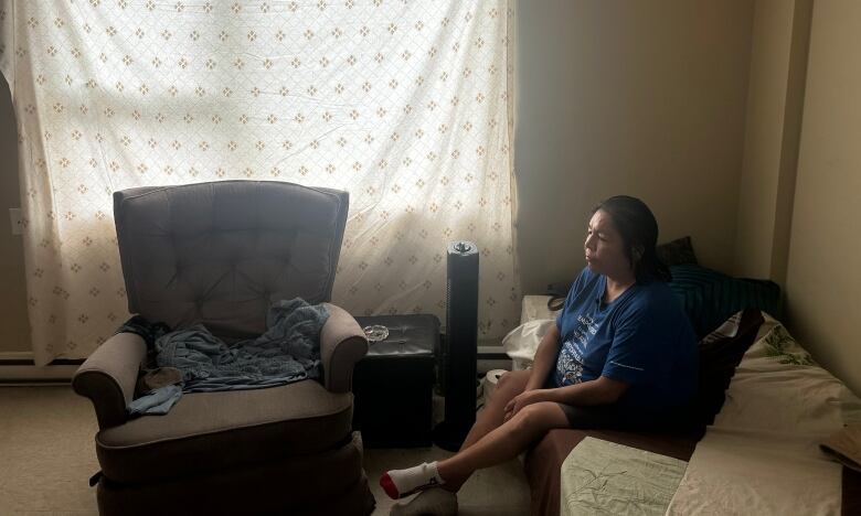 Debbie Thunder battles the heat with a fan and a sheet to block out the sun. She would like to move to a place with better air circulation. 