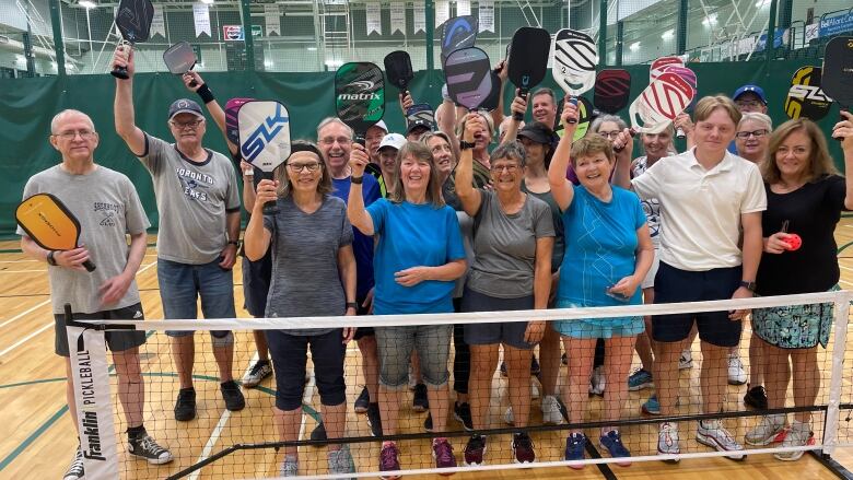 A group of pickleball players holding up their racquets 