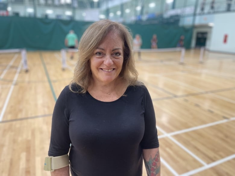 A woman standing next to a pickleball game 